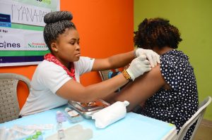 A healthcare professional administering hpv vaccine into the upper arm of a seated woman