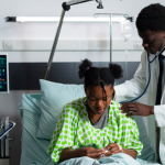 hepatitis b: A male doctor and female nurse attend to a patient in a Nigerian hospital bed.