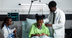hepatitis b: A male doctor and female nurse attend to a patient in a Nigerian hospital bed.